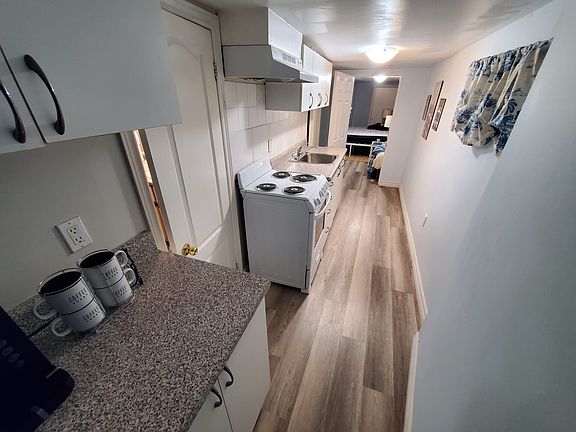 Galley style kitchen with new stove, coffee maker, storage cabinets