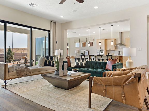 Spacious gathering room lit by overhead lighting and the large sliding glass doors to the backyard.