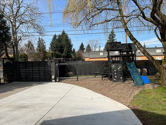 Front yard with Paved parking, gated fence and play structure.