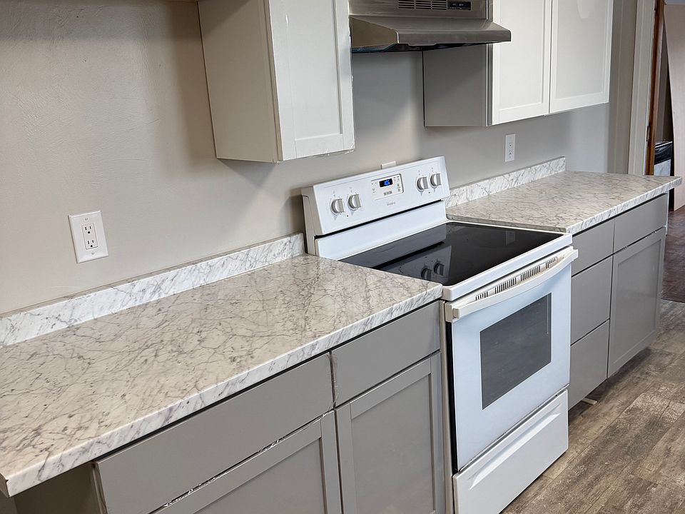 Renovated kitchen includes electric oven, dishwasher, refrigerator, and microwave.