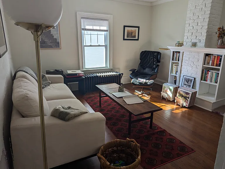 Spacious living room with west facing large window. Custom book cases, hardwood floors and the original radiator make for a charming space for hanging out.