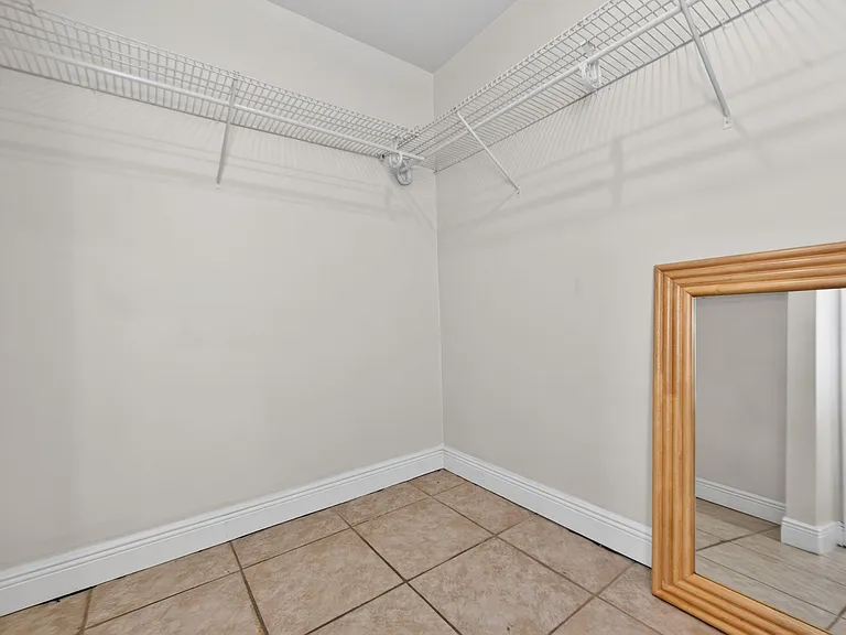 Walk-in closet with tiled flooring, wraparound wire shelving, and ample hanging space for organized storage.