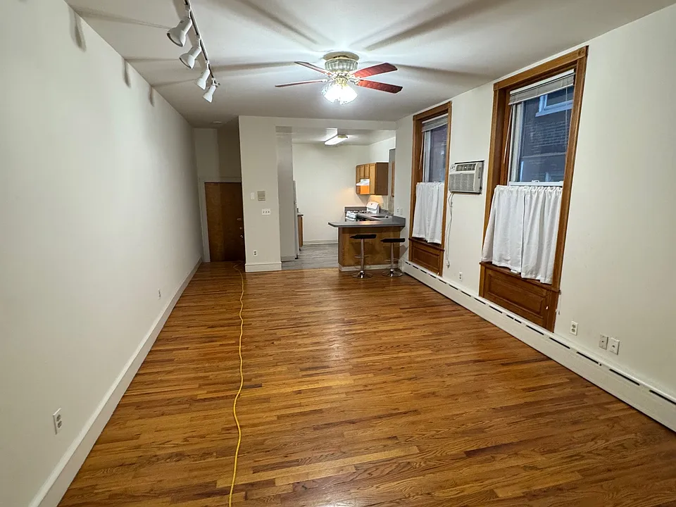 Living room, and dining area with a track light on the left, ceiling fan with light. two large windows