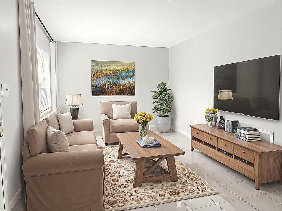 Bright and inviting living room with modern beige sofas, a sleek wooden coffee table, and a wall-mounted TV; ideal for comfortable living and entertaining.