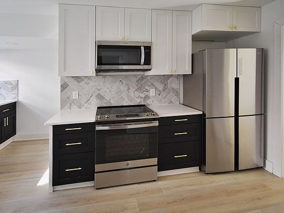 Modern kitchen with brand new stainless steel appliances including electric stove, refrigerator, microwave and dishwasher