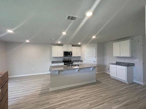 Kitchen w/ walk-in pantry and stainless steel fridge, stove, and microwave.
