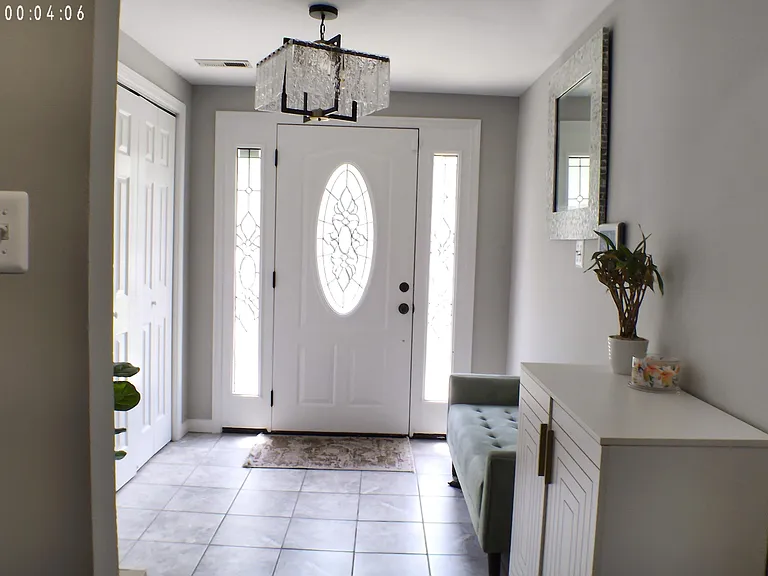 Inviting entry foyer with tiled flooring, decorative front door sidelights, and space for a bench and console storage.