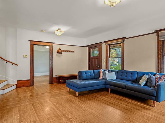 View of the door to the front bedroom to the left, front door to the right, and large windows that face 24th street.