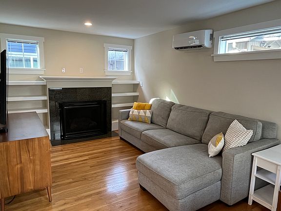 Main floor (second floor) living room area with gas fireplace, built in shelves, lots of windows for natural light and new smart mini-split for AC & heating.