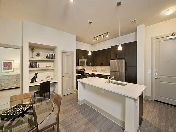 Open-concept gourmet kitchens with stainless steel appliances, granite slab countertops, custom cabinentry, and natural stone backsplash.