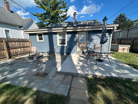Backyard cement porch and stone patio with table, chairs and fire pit.
