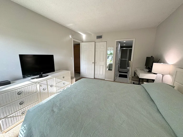 Master bedroom with view into master bathroom closet and furniture and exit into living room