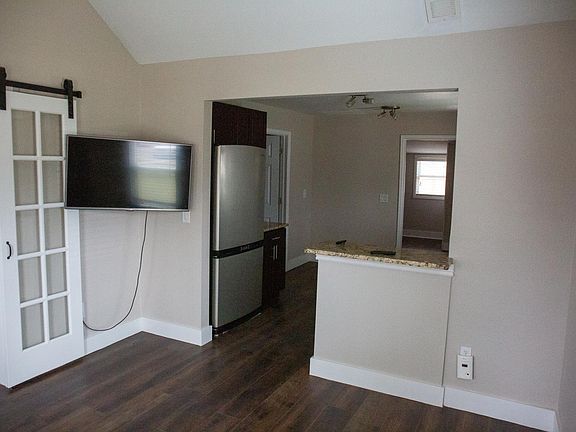 Living room with TV included, leading into the kitchen, with second bedroom/office on the left.