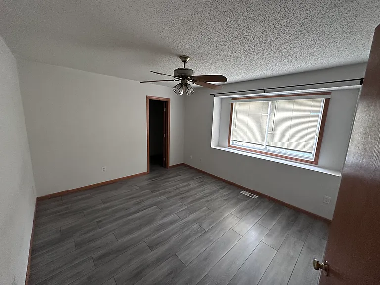 Primary bedroom with ceiling fan and wide window