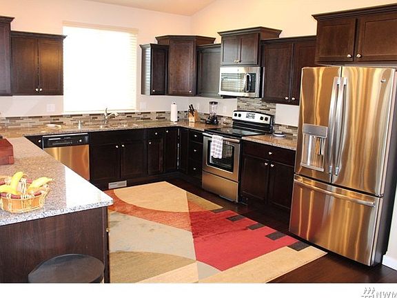 Dream kitchen with wood floors, slab granite counters, stainless appliances and rich dark cabinets.