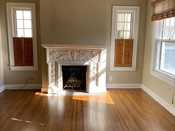 Original hardwood floors and decorative fireplace in the spacious living room.