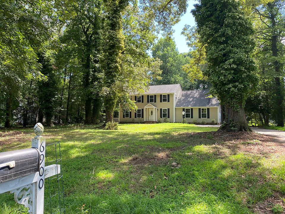 View from street, driveway wraps around to the right side of the house, leading to a spacious 2-car garage