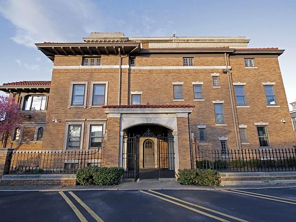 Side view of building. car port, black gate, and onsite parking.