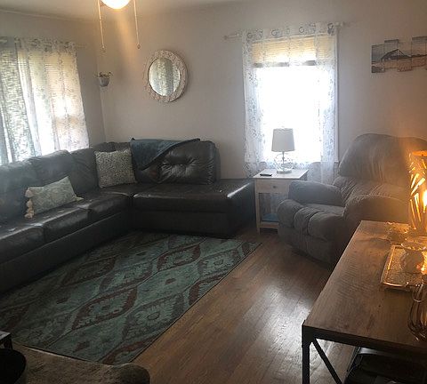 Spacious living room with newly refinished hardwood floors, new ceiling fan, new paint throughout.