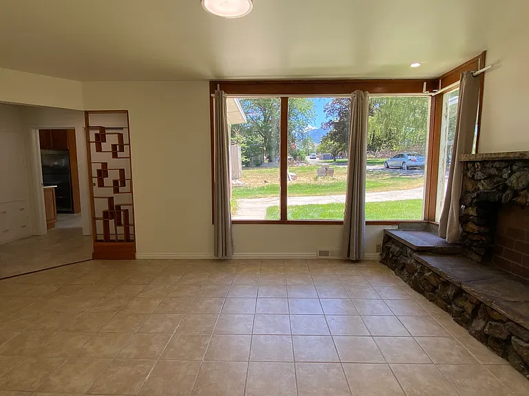 Living Room: As you entered the foyer, there is an original built-in shelf for special items. The corner windows have a view of the front. Tile floors and a rock fireplace and mantle. Very bright room during the morning and throughout the day.