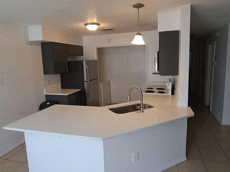 Open kitchen with a large peninsula, integrated sink, ample counter space, and full-size appliances for easy meal prep.