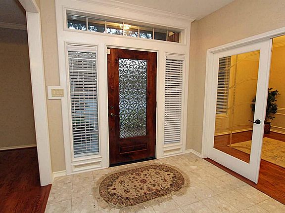 The entry has a marble floor and a custom door with decorative glass insert.  To the right is the dining room with custom French doors so that it can also be used as a study.