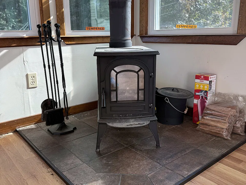A permitted wood-burning stove on a tiled hearth, ready for the first cold night.