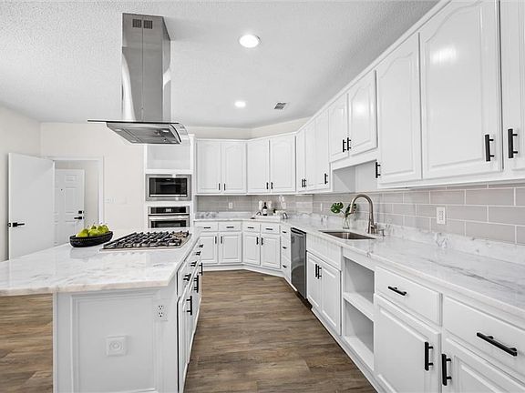 Kitchen featuring island exhaust hood, sink, a kitchen island, white cabinetry, and dark hardwood / wood-style flooring