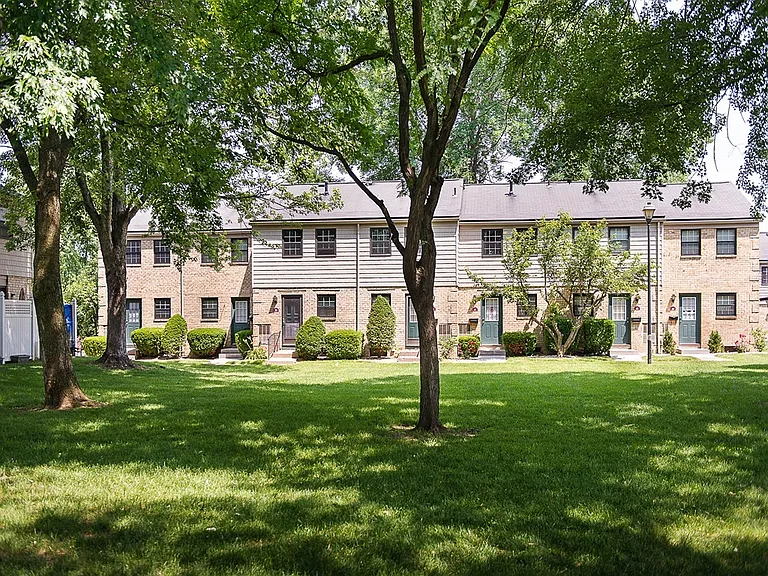 Exterior view from treed courtyard of private entrances to apartment homes