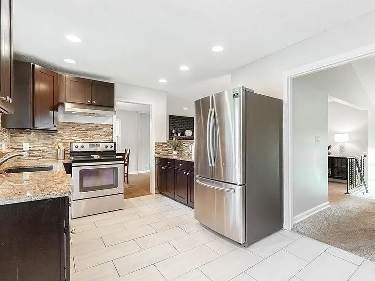 Chef-ready kitchen with stainless steel appliances, granite counters, tile backsplash, and generous cabinet storage.