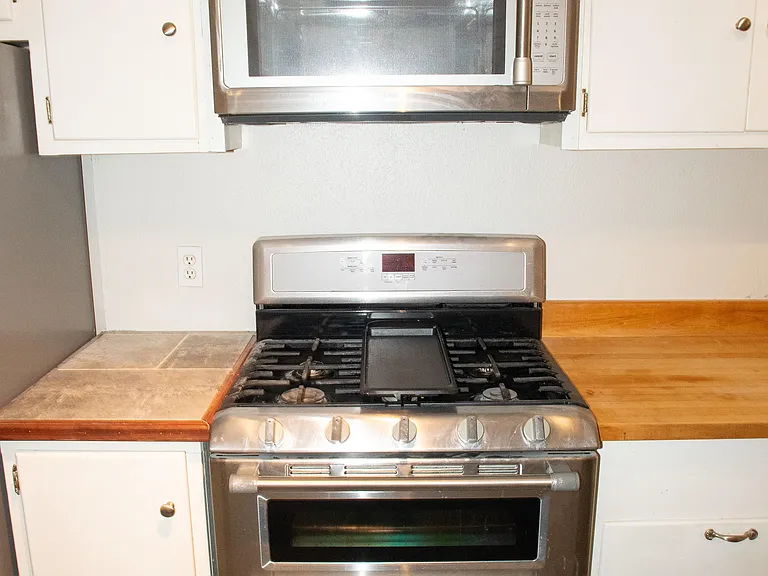 Full kitchen features plenty of cabinet space with a microwave, stove, oven, and two refrigerators.