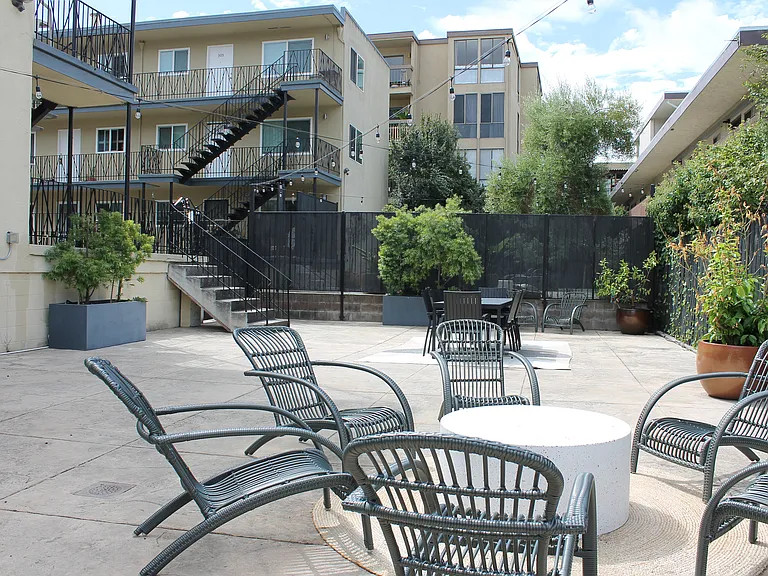 Charming apartment complex courtyard featuring stylish outdoor seating, lush greenery, and modern architectural design. Charming apartment complex courtyard featuring stylish outdoor seating, lush greenery, and modern architectural design.