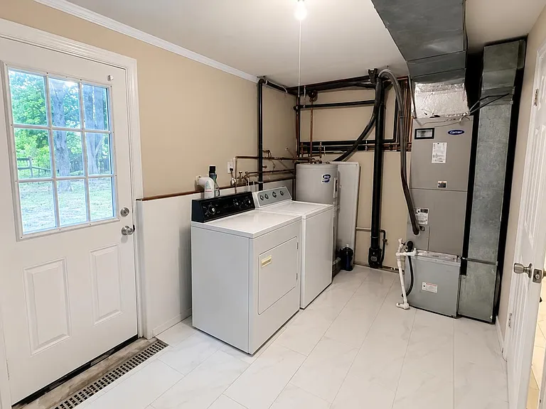 Dedicated laundry/utility room with full-size washer and dryer, tiled flooring, and exterior door access.
