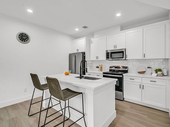 Eat-in kitchen with large island, stainless appliances, and ample white cabinetry for everyday cooking and storage.