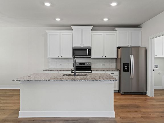 The kitchen has beautful white cabinetry.