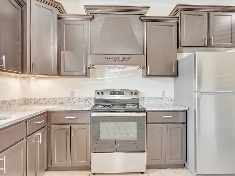 Stylish kitchen with gray cabinets and stainless steel appliances, located in Merida Vista Apartments, Laredo, Texas