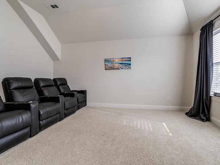 Home theater with vaulted ceiling and carpet