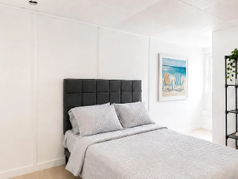 Well-appointed bedroom with a full bed, upholstered headboard, and open shelving for storage and display.