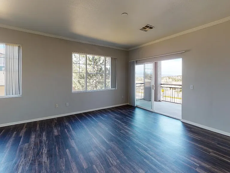 Apartment living room with wood-style flooring and patio or balcony in select homes.