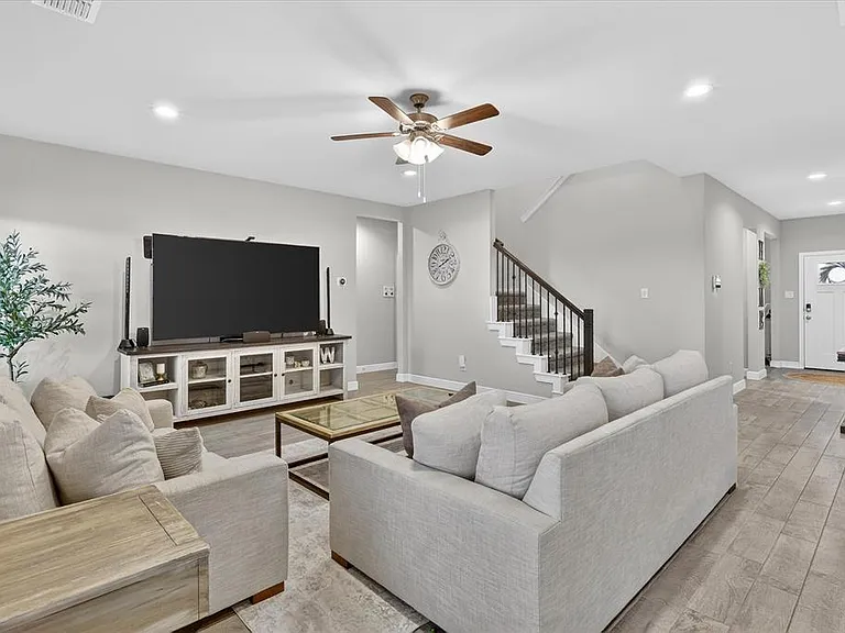 Spacious living area featuring light-toned wood-finish flooring, recessed lighting, and a ceiling fan