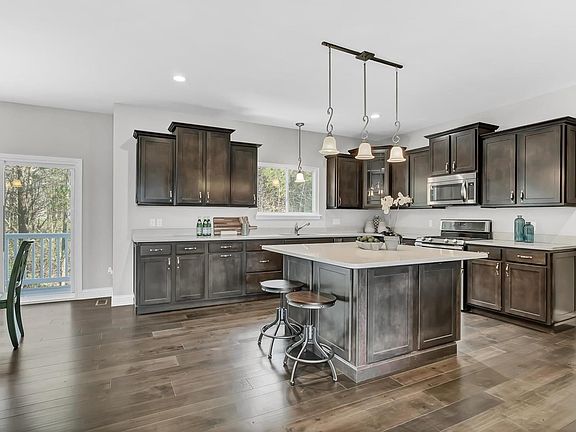 The vast Kitchen is has a plethora of soft close cabinets.  Over sized island has two sided overhang for additional seating.  Stainless appliances, Gas range, built in microwave, walk in pantry.  Main floor laundry is to the right in this pic, has a window for natural lighting and plumbed for a sink.