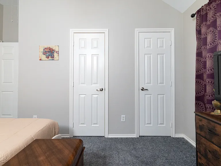 Bedroom 3 features soft neutral bedding, wall art, a TV, room-darkening curtains and a cozy atmosphere. Ideal for resting after a long day, with towels provided for your stay.