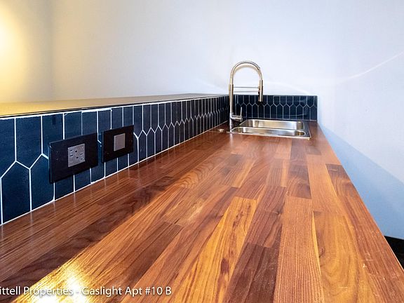 Blue tile backsplash, wood finish countertop, double sink