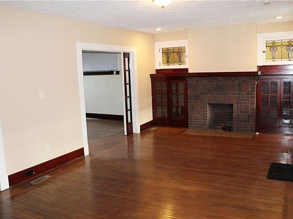 Living Room: Glorious stained glass windows frame the mahogany built in bookcases and brick fireplace providing a preview of the