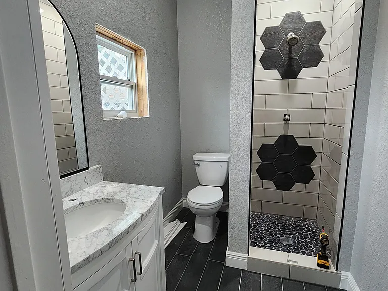 Bathroom with tile shower and flooring. Quartz countertop