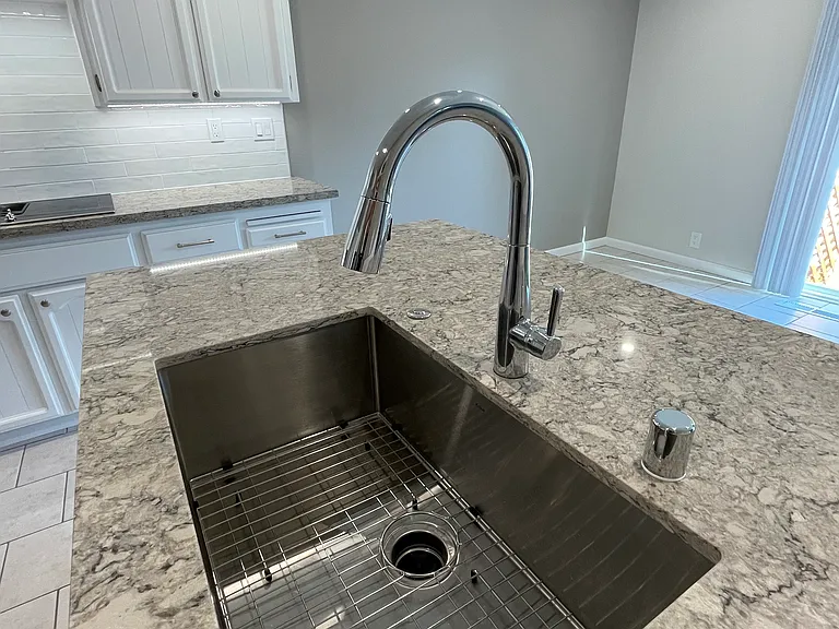 Beautiful new countertops on island, with new easy-to-clean stainless steel sink and polished chrome faucet.