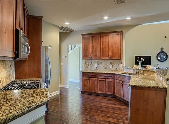 The kitchen features high-quality granite counters, custom backsplash and rich wood flooring.