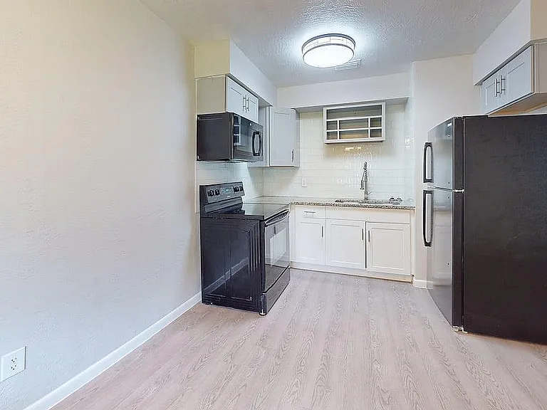 Modern kitchen with sleek black appliances, granite countertops, and ample cabinet space, perfect for culinary enthusiasts.