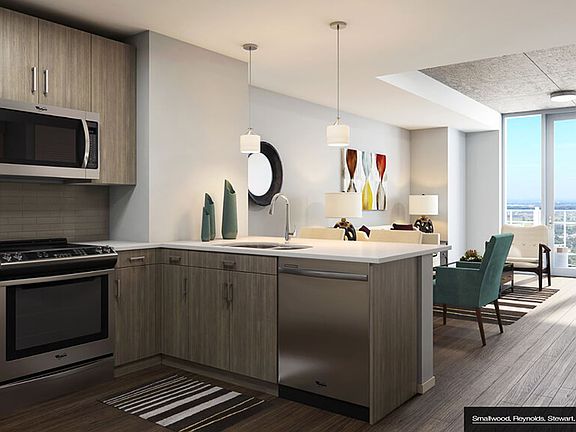 Stunning open kitchen and living room concept with stainless steel appliances, wood plank flooring, pendant lighting and quartz countertops