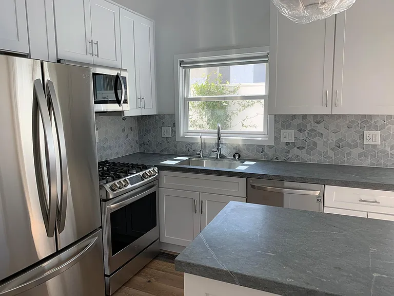 Stainless steel appliances, stone tile backsplash, and granite countertops.